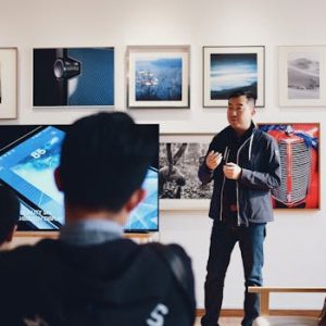 Man giving a presentation in a modern art gallery setting, engaging audience.